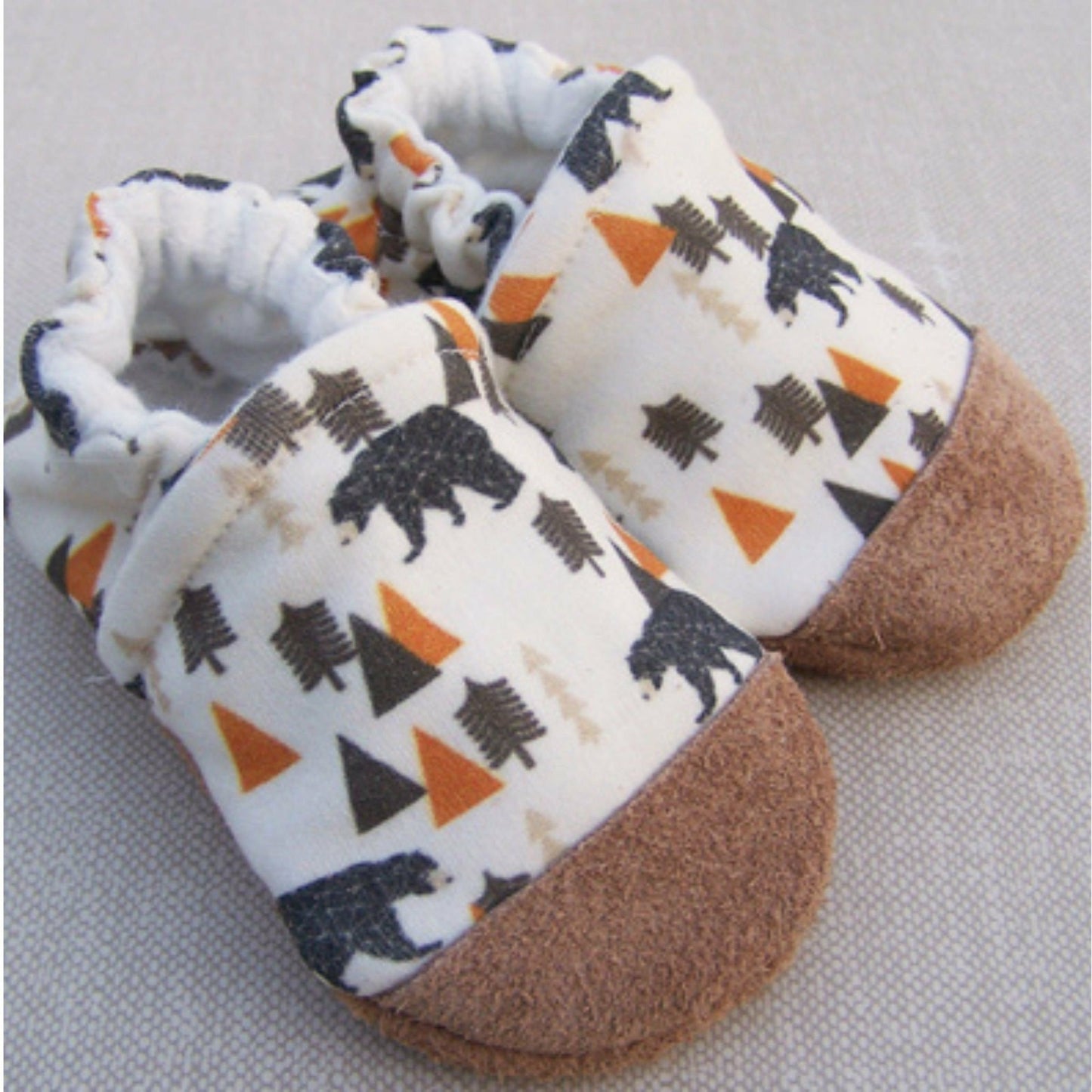 Organic cotton white fabric with black bear, orange, and dark brown trees. Infant slipper with soft leather sole